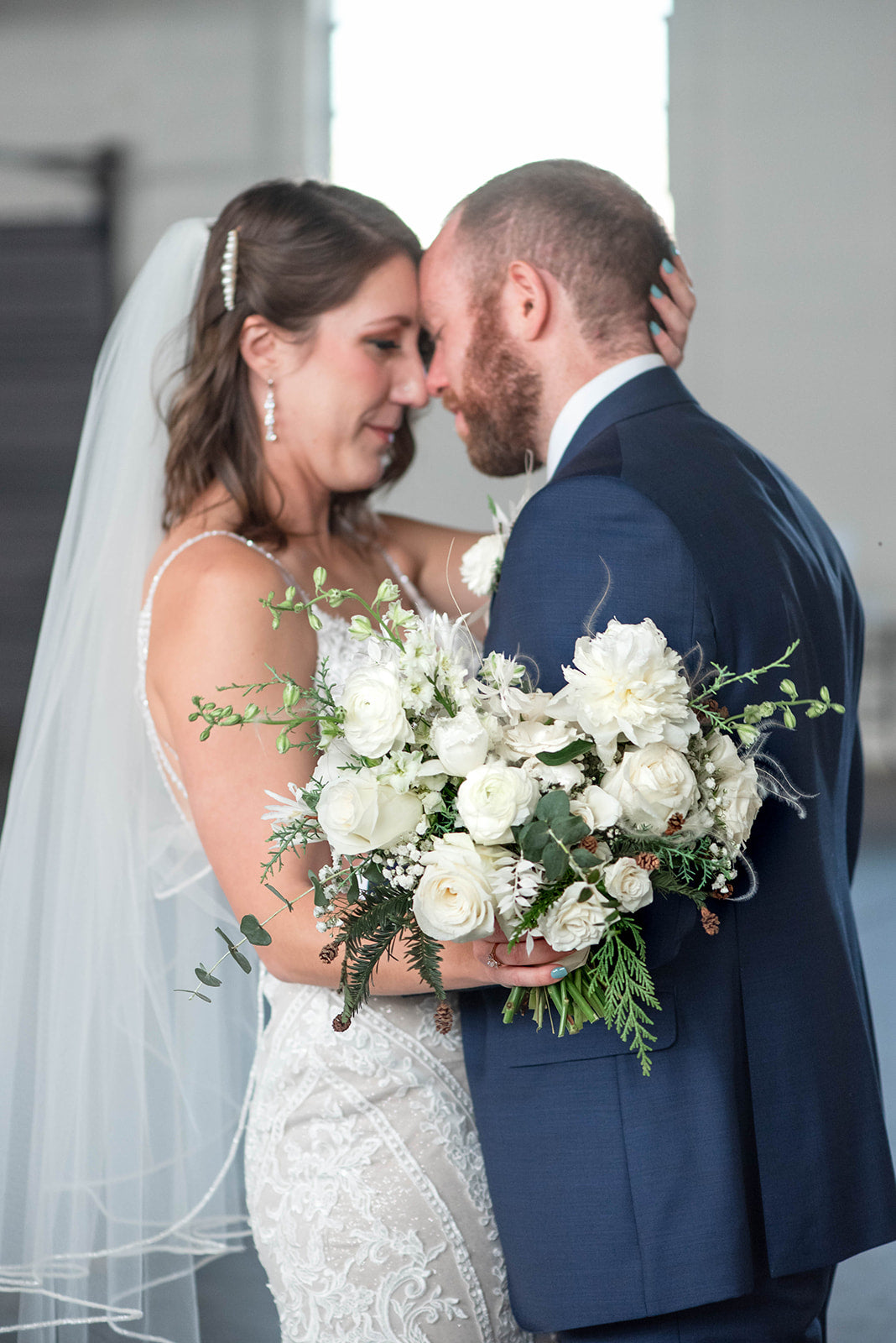 White roses, white ranunculus, white larkspur winter wedding bouquet, expertly crafted by a Memphis, TN-based boutique floral design studio. The ultimate choice for a fairytale wedding.