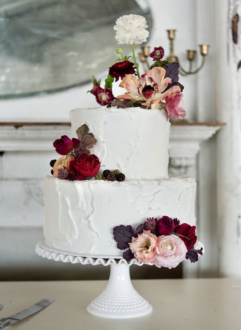 Picture of white wedding cake featuring small flower arrangements on varying levels of the cake.  Floral arrangement completed by Everbloom Design a Memphis, Tennessee flower shop.