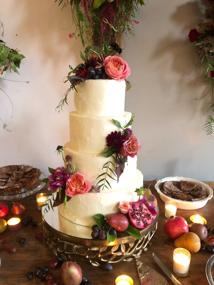 Picture of white wedding cake featuring small flower arrangements on varying levels of the cake. Floral arrangement completed by Everbloom Design a Memphis, Tennessee flower shop.
