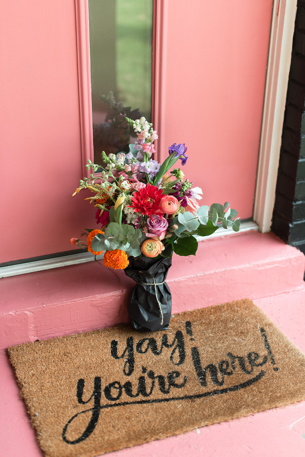 Blue Iris, red dahlia, peach ranunculus in a paper wrapped vase, as captured in the studio of a Memphis, TN-based boutique floral design studio. The perfect choice for a romantic and timeless wedding