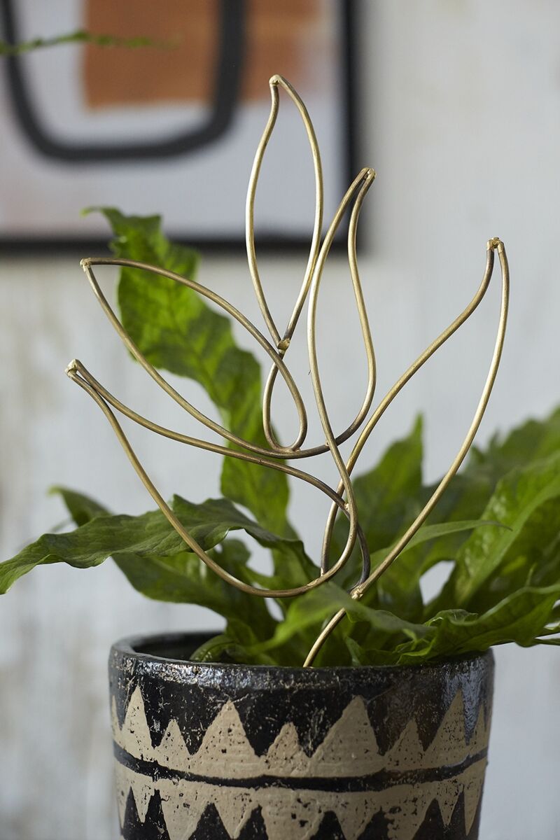 Decorative plant with gold leaf-like trellis structure in a pot with a geometric design.