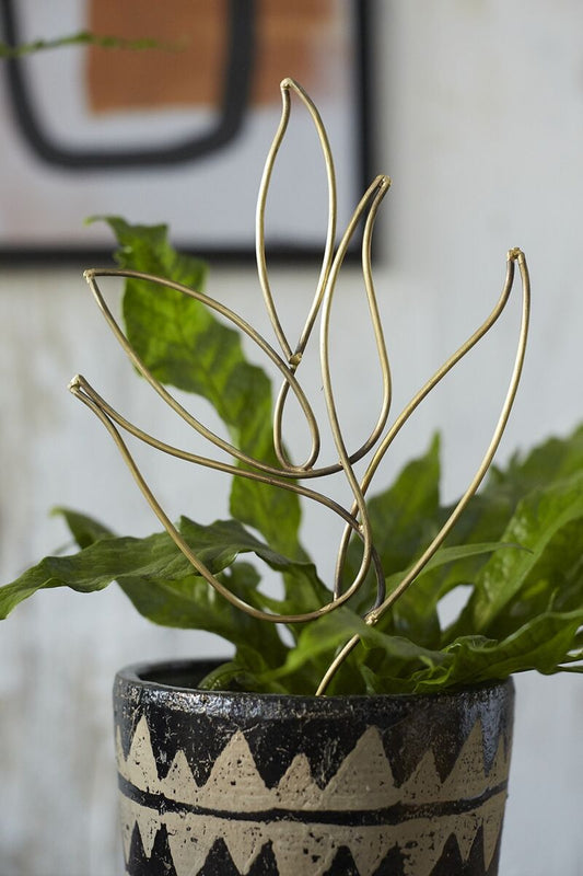 Decorative plant with gold leaf-like trellis structure in a pot with a geometric design.