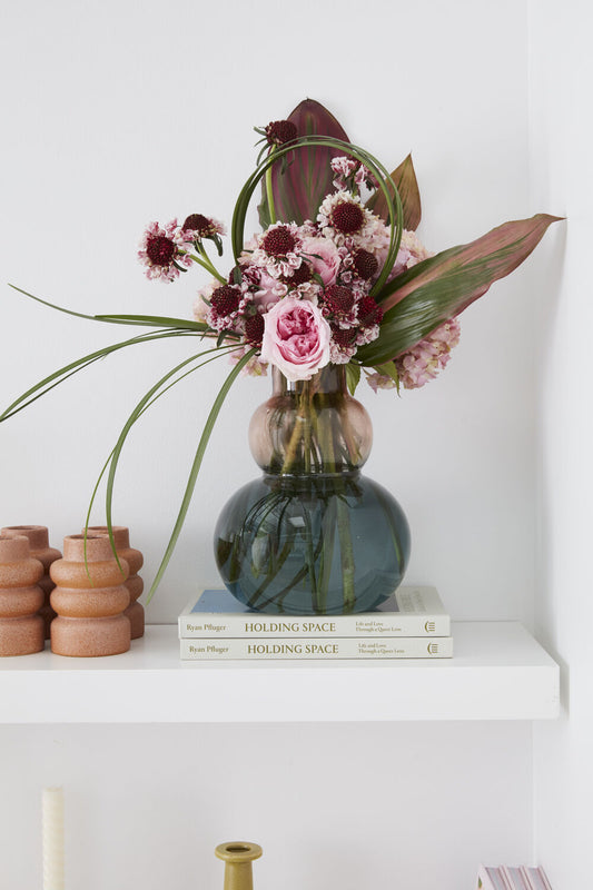 Decorative vase with flowers on a shelf with books