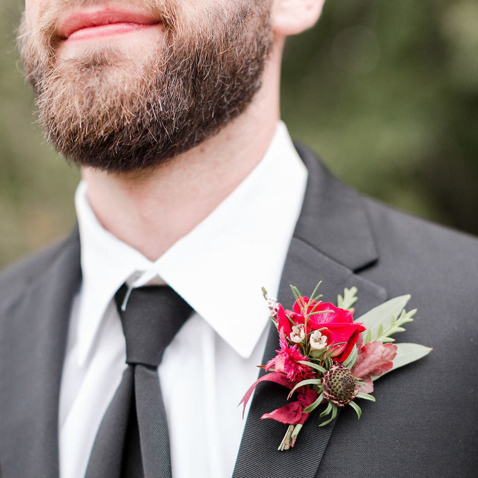 Boutonniere pinned to male suit lapel with red flowers.  Floral arrangement completed by Everbloom Design a Memphis, Tennessee based floral studio.