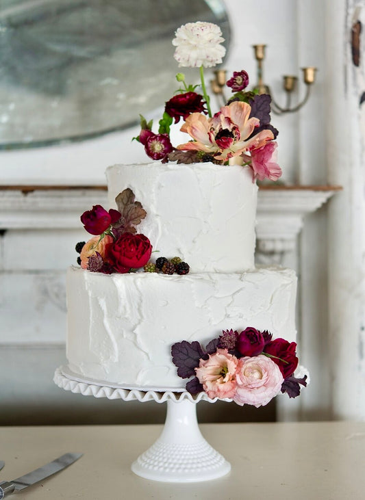 Picture of white wedding cake featuring small flower arrangements on varying levels of the cake.  Floral arrangement completed by Everbloom Design a Memphis, Tennessee flower shop.